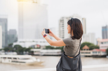 Happy solo Southeast Asian woman teenager blogger and travel explorer take photo with smartphone....