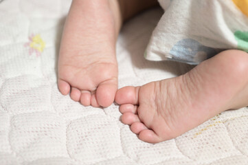 cute baby sleeping on bed with feet close-up shot