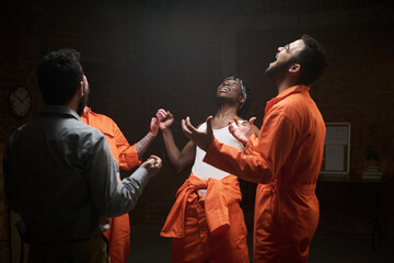 Group of young adult multiethnic men standing in circle holding hands participating in group...