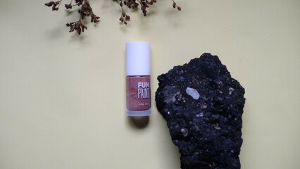 Glass bottle containing light brown liquid with white cap is placed on piece of weathered wood provides textured and natural element creating balanced aesthetic to the composition. 