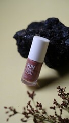 Glass bottle containing light brown liquid with white cap is placed on piece of weathered wood provides textured and natural element creating balanced aesthetic to the composition. 