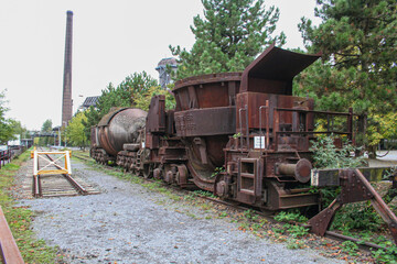 An old, rusty industrial train, possibly a locomotive or wagon, sits abandoned on a railway track...