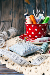 Colorful sewing supplies with pin cushion and threads on rustic handmade crochet background