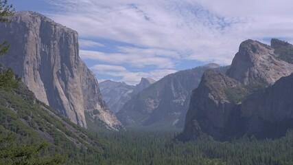 Footage of a medium shot from the famous Tunnel View overlook in Yosemite National Park, California, featuring the iconic granite cliffs of El Capitan and the distant peak of Half Dome.