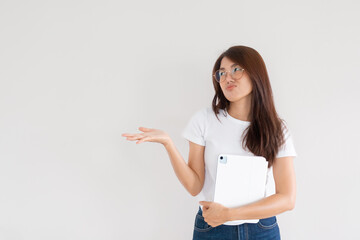 Unhappy Asian Thai woman wear glasses holding tablet and presenting with hand isolated over white...