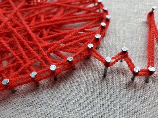 Creative yarn art project showcasing intricate pattern creation using bright red thread wound...