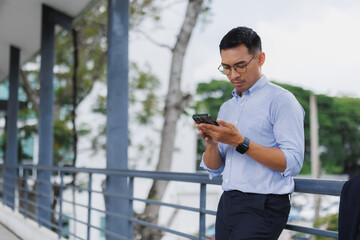 Young businessman reading messages on his smartphone outdoors