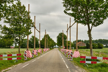 Naklejka premium High voltage line under construction with wooden traffic protection and warning shields on polder road in rural in Zeeland, Netherlands, Europe