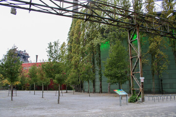A large industrial building with green-paneled walls and exposed metal structures in...