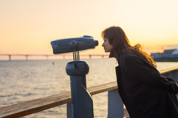 Girl looking in binoculars telescope for tourist. Travel, budget tourism, outdoor lifestyle holiday vacation. Side view