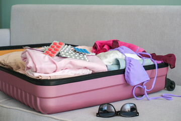 Women's clothing and pills in a travel bag. Concept of medication required in journey