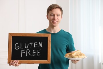Man holding small chalkboard with text Gluten Free and pretzels indoors