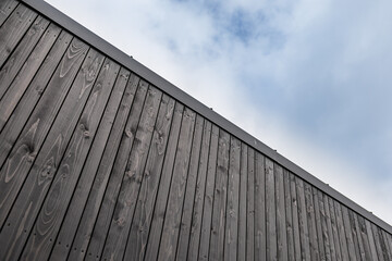 Fototapeta premium Dark Wooden Wall Against Cloudy Blue Sky