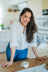 Young woman drinking hot coffee at home in the kitchen.