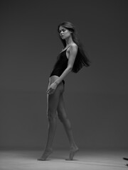 black and white woman walking gracefully in a simple black bodysuit with long hair, elegant pose, studio background, minimalist style, artistic mood