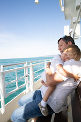 A man and a boy on a white boat in the sea are sitting by the side, father and son are enjoying a sea trip