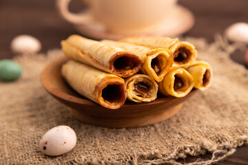 Waffles with caramel on brown wooden, linen textile, cup of coffee, side view, selective focus