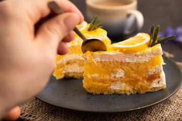 Lemon cake with hand on black concrete, linen textile, cup of coffee, side view, close up,...