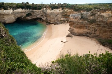 Dramatic coastal scene of Loch Ard Gorge's Shipwreck Point. Rugged cliffs frame a small sandy beach...