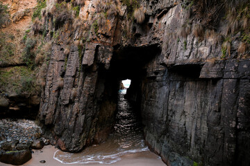Remarkable Cave at Port Arthur, Tasmania. Waves crash against the eroded rock, highlighting the...
