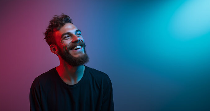 Smiling man with curly hair enjoys vibrant lighting in a studio setting, reflecting joy and positivity during a creative photoshoot