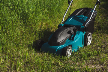 Electric Lawn Mower on Green Grass Field in Summer Garden