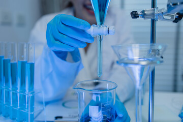 two scientists consult each other while conducting an experiment on a liquid substance in a...