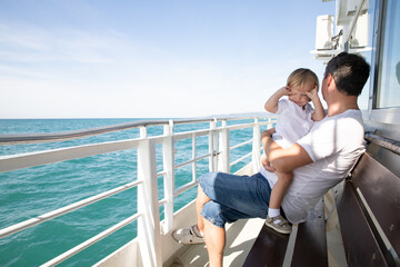 A man and a boy on a white boat in the sea are sitting by the side, father and son are enjoying a sea trip