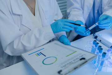 two scientists consult each other while conducting an experiment on a liquid substance in a...