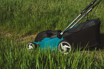 Electric Lawn Mower Cutting Grass in Garden on Sunny Day