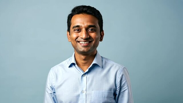 Smiling Indian man in a light blue shirt, studio shot