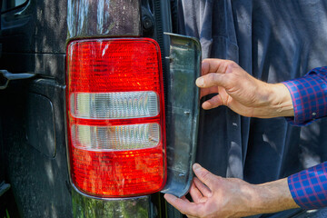 installing a car taillight, a man removes a plastic plug in a car's taillight, repair of a taillight, spare parts for cars