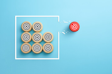 Target icon on wooden cube breaking through obstacle on blue background, Concept of overcoming barriers