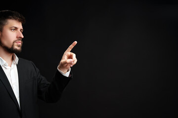 Man in a suit gestures confidently while speaking during a formal presentation in a dimly lit room