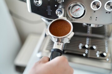 Espresso machine in the kitchen. A close up view of a man's hand holding a portafilter