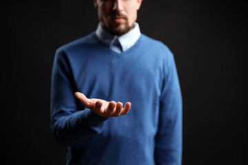 Man reaching out with open hand in a dark setting, conveying invitation or request for assistance