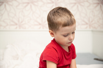 Sad little boy sitting in red t-shirt and almost crying, breathing nebulizer