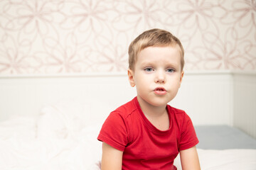 Sad little boy sitting in red t-shirt and almost crying, breathing nebulizer