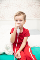 Sad little boy sitting in red t-shirt and almost crying, breathing nebulizer