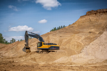 A caterpillar tractor works with a bucket in a sand pit. Sand mining