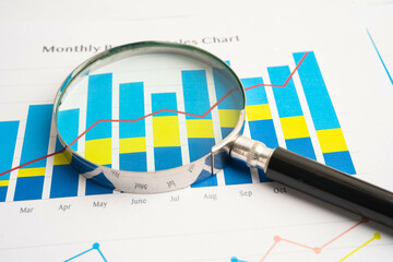 Magnifying glass on data business graphs paper.