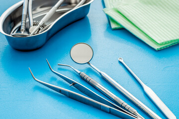 Dental instruments in stainless steel tray on blue background close up