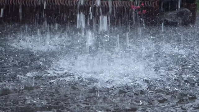 Heavy rain pours and water flows rapidly from the house&rsquo;s gutters, illustrating intense rainfall and drainage in action.