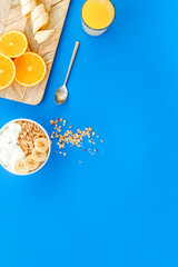 food for healthy breakfast with granola and fresh orange juice on bright blue background top view mock up