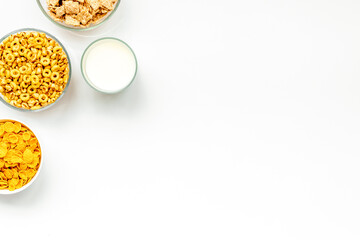 Various cereals in bowls and milk on white background top view copyspace