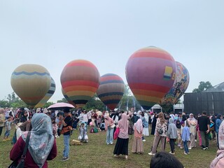 Colorful hot air balloons festival display distinct horizontal stripes are being inflated on the cloudy sky provide  backdrop. 