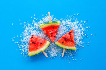 Slices of watermelon popsicle on blue background top view