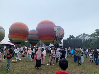 Colorful hot air balloons festival display distinct horizontal stripes are being inflated on the cloudy sky provide  backdrop. 
