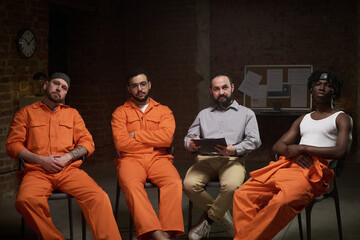 Group of young adult men sitting in circle participating in group therapy session in prison setting...