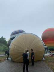Colorful hot air balloons festival display distinct horizontal stripes are being inflated on the cloudy sky provide  backdrop. 